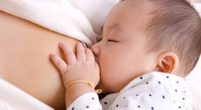 Imagem de um bebê mamando no peito da mãe