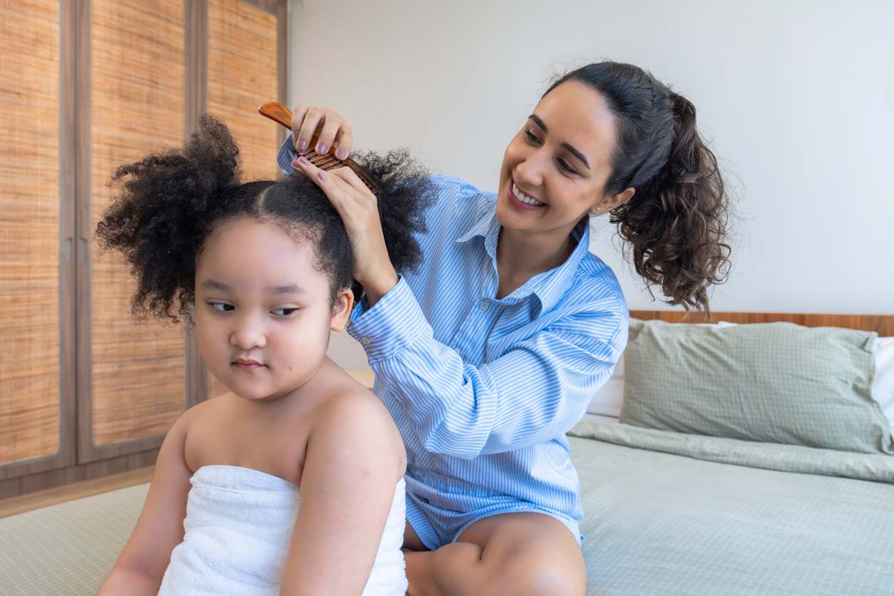 Mãe fazendo penteado no cabelo da filha