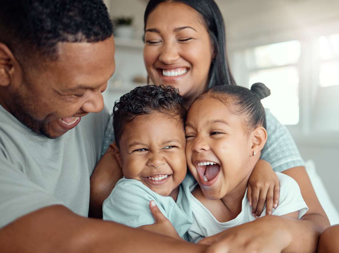  Família feliz se abraçando. Temos papai, mamãe, irmãozinho e irmãzinha, todos usando camiseta verde menta pastel.