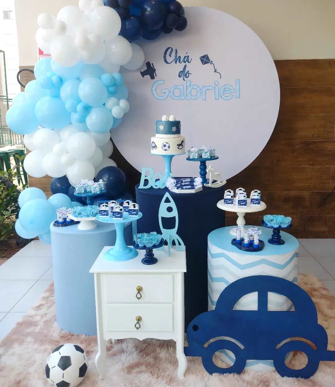 Decoração de chá de bebê azul com tema de carros e balões.