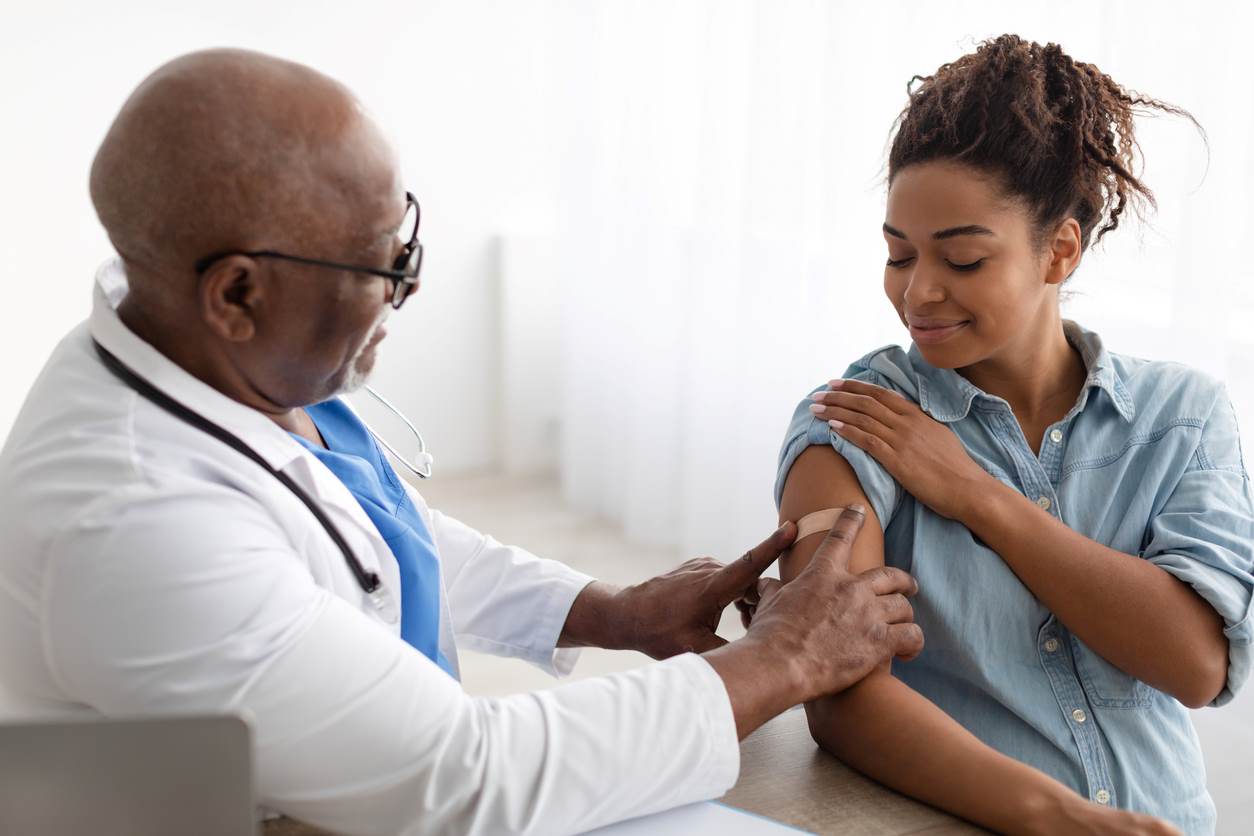 Paciente recebendo vacina de médico em consultório.