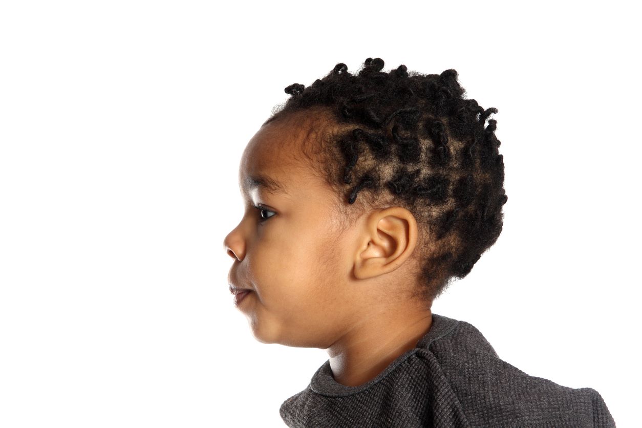 Menino pequeno de perfil, com penteado de torcidinhos no cabelo crespo