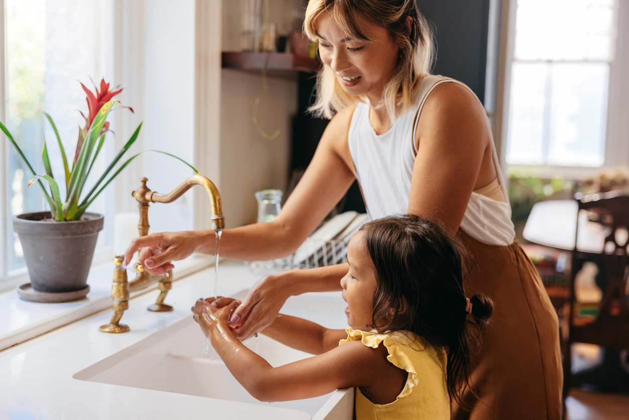 Mãe ajudando filha a lavar as mãos 