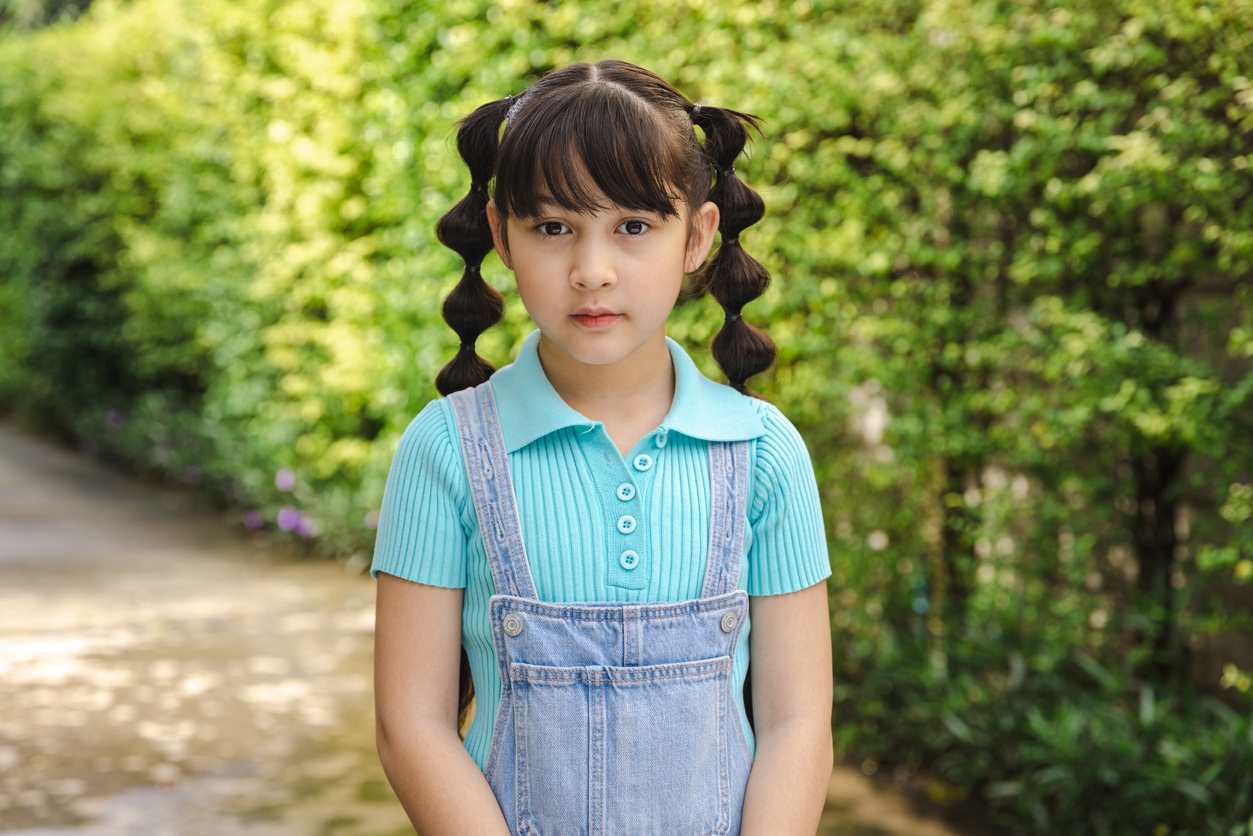 Menina com penteado infantil de tranças com laços.