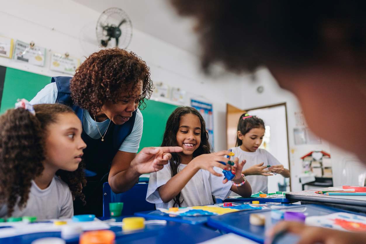 Professora orienta crianças na sala de aula