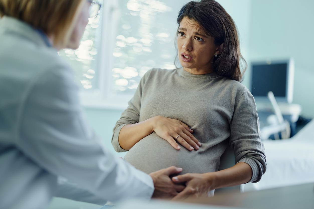 Mulher grávida em consulta médica, com expressão de preocupação