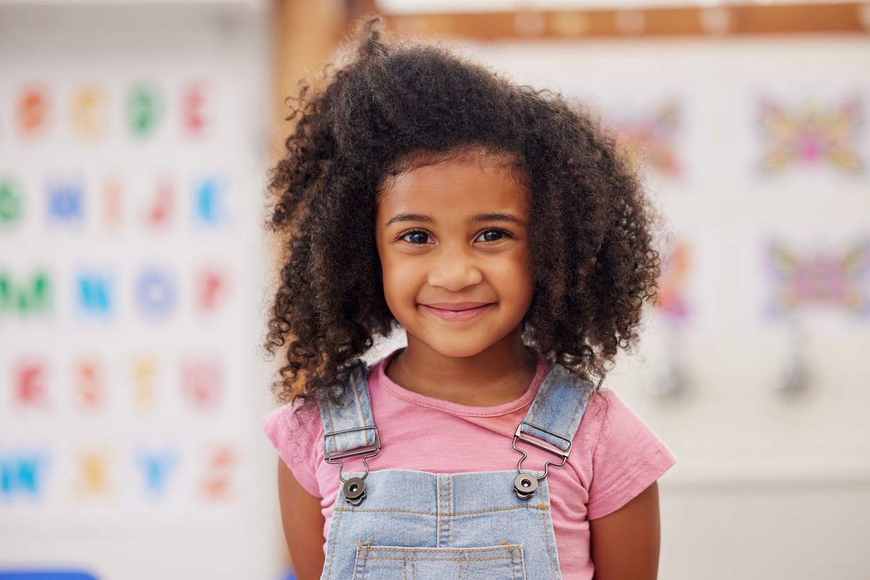 Menina na escola, feliz com seu cabelo semipreso para o lado