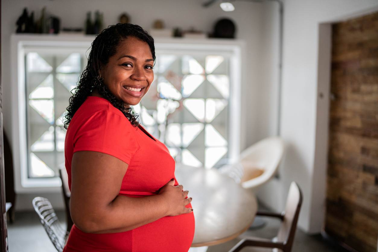 Mulher grávida sorrindo em casa.