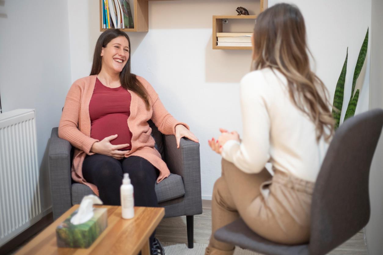 Mulher grávida sentada e sorrindo durante consulta