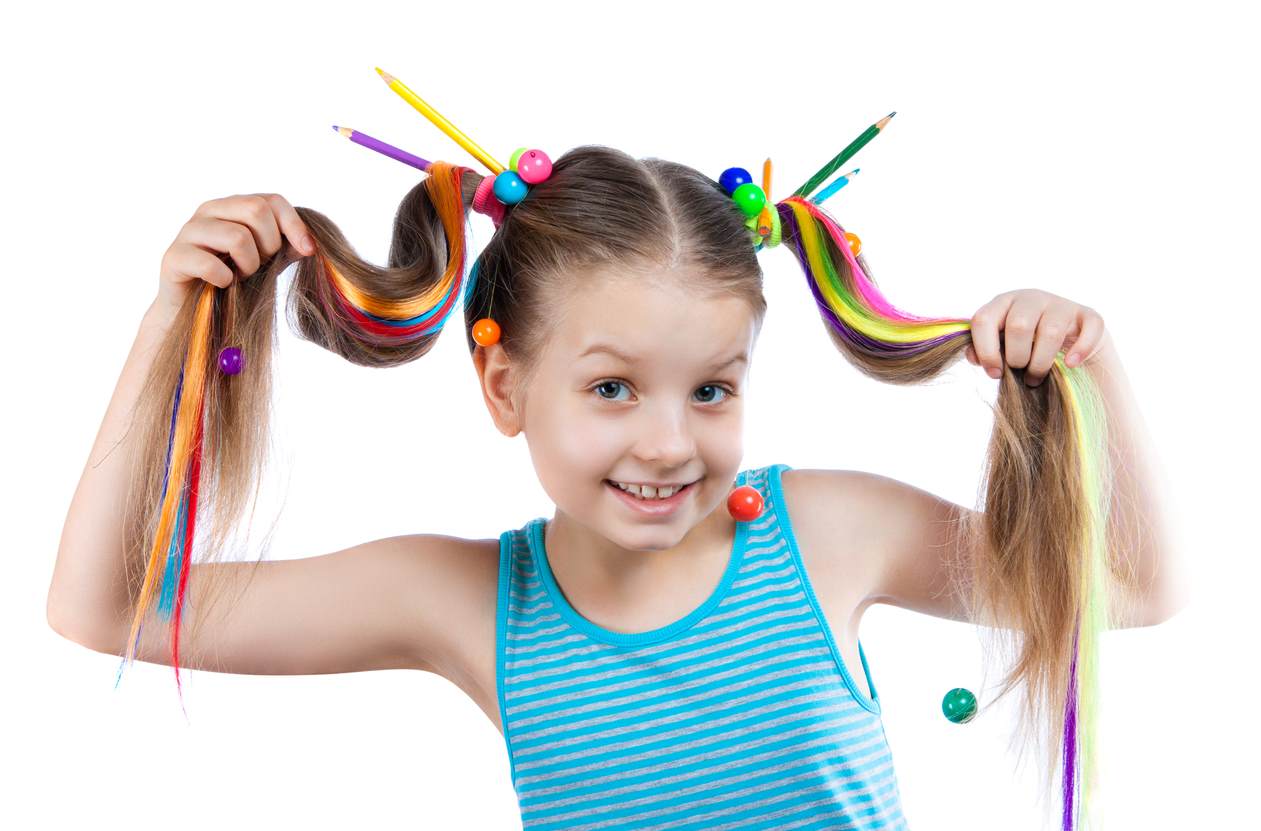 Menina segurando mechas de penteado maluco, colorido, com aplicação de fitas, lápis de cor e bolas coloridas.