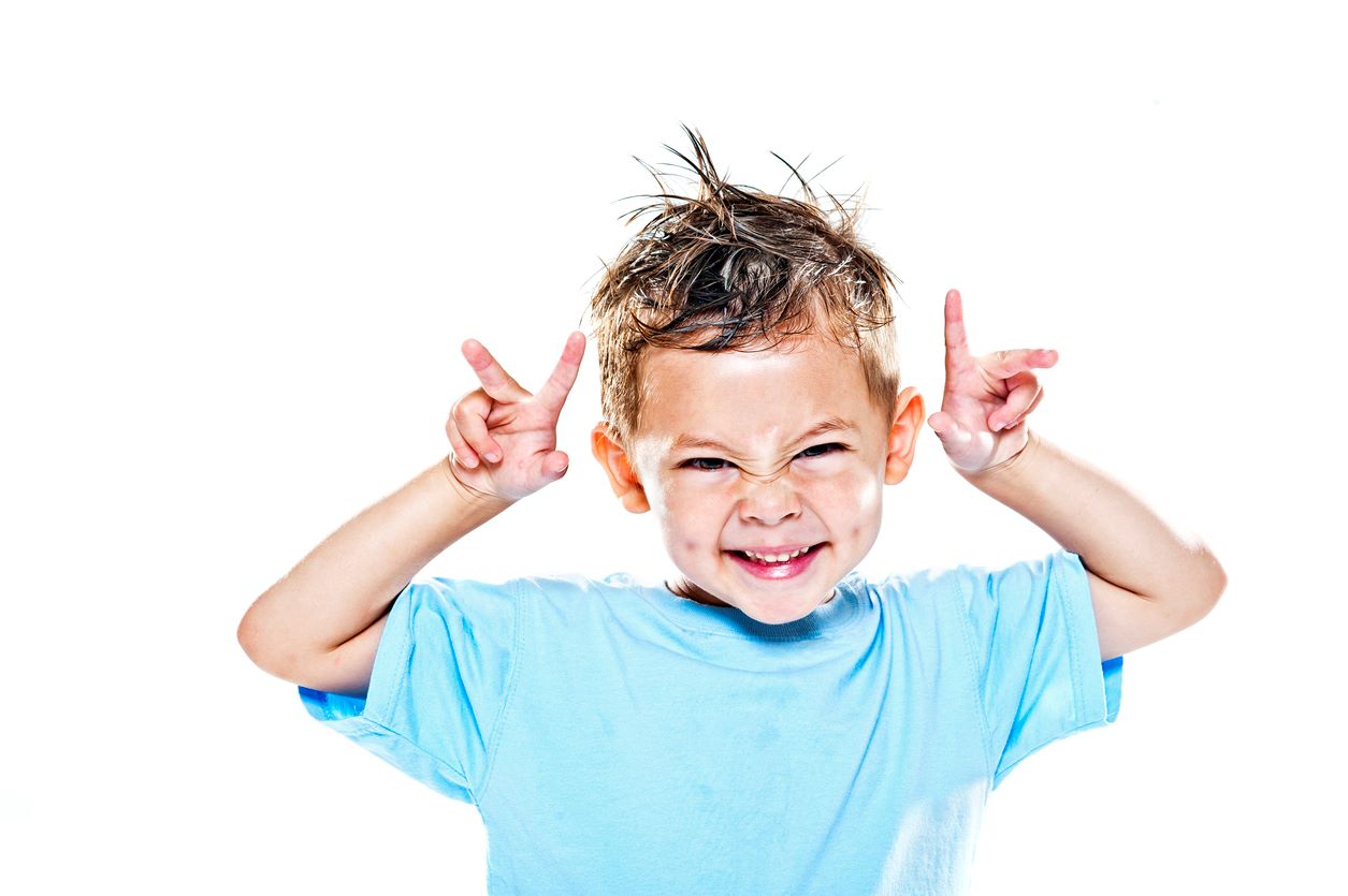 Menino com cabelo espetado fazendo careta divertida para a foto.