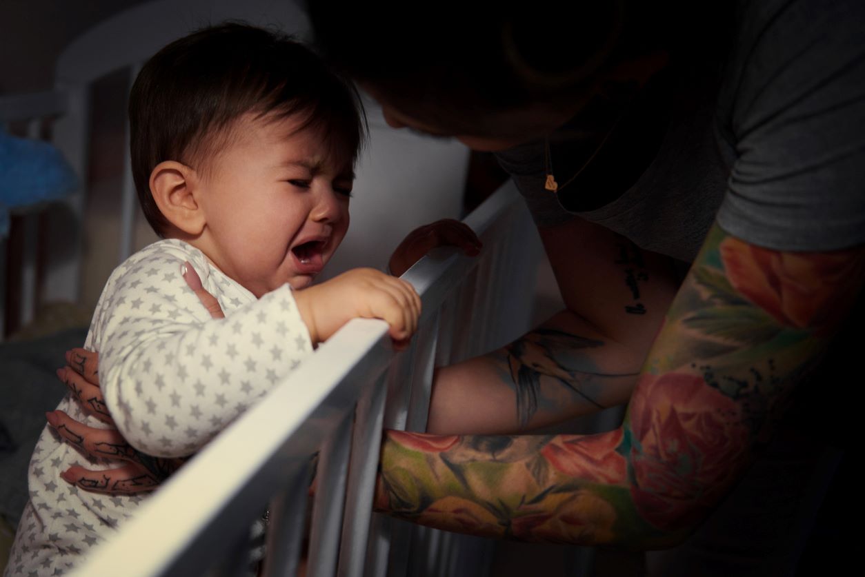 Bebê chorando no berço durante a noite.